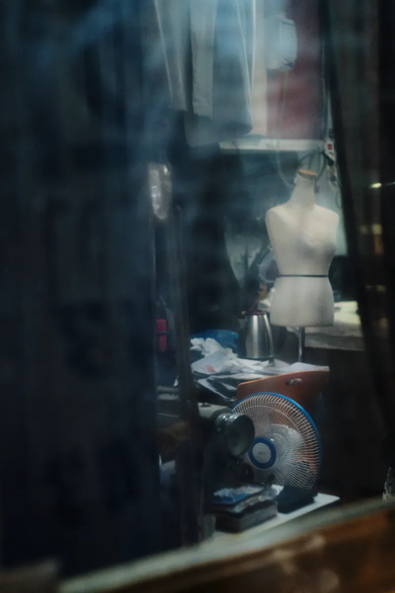Dark shop window with a mannequin torso and tools