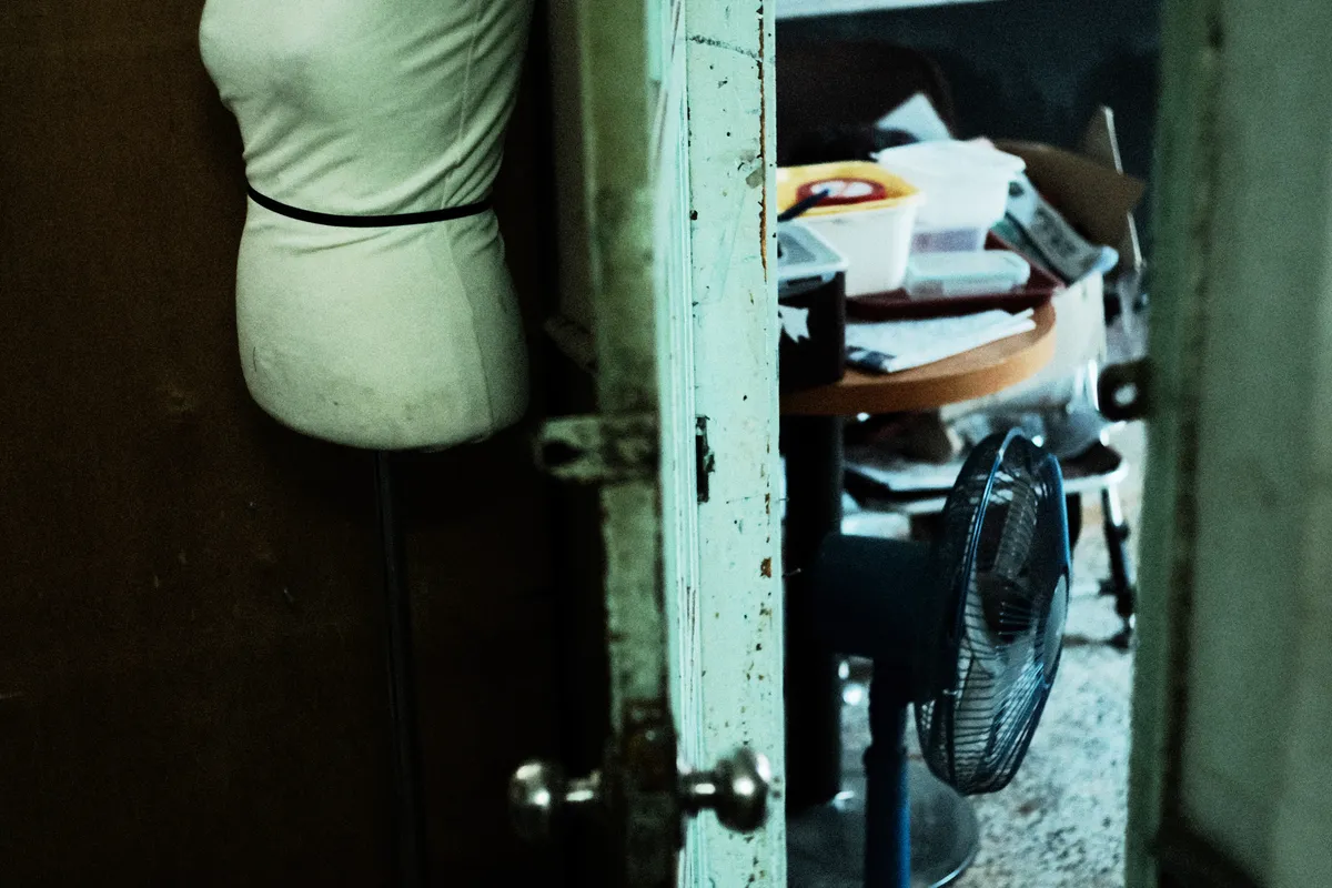 Mannequin torso beside an open door in a tailor shop
