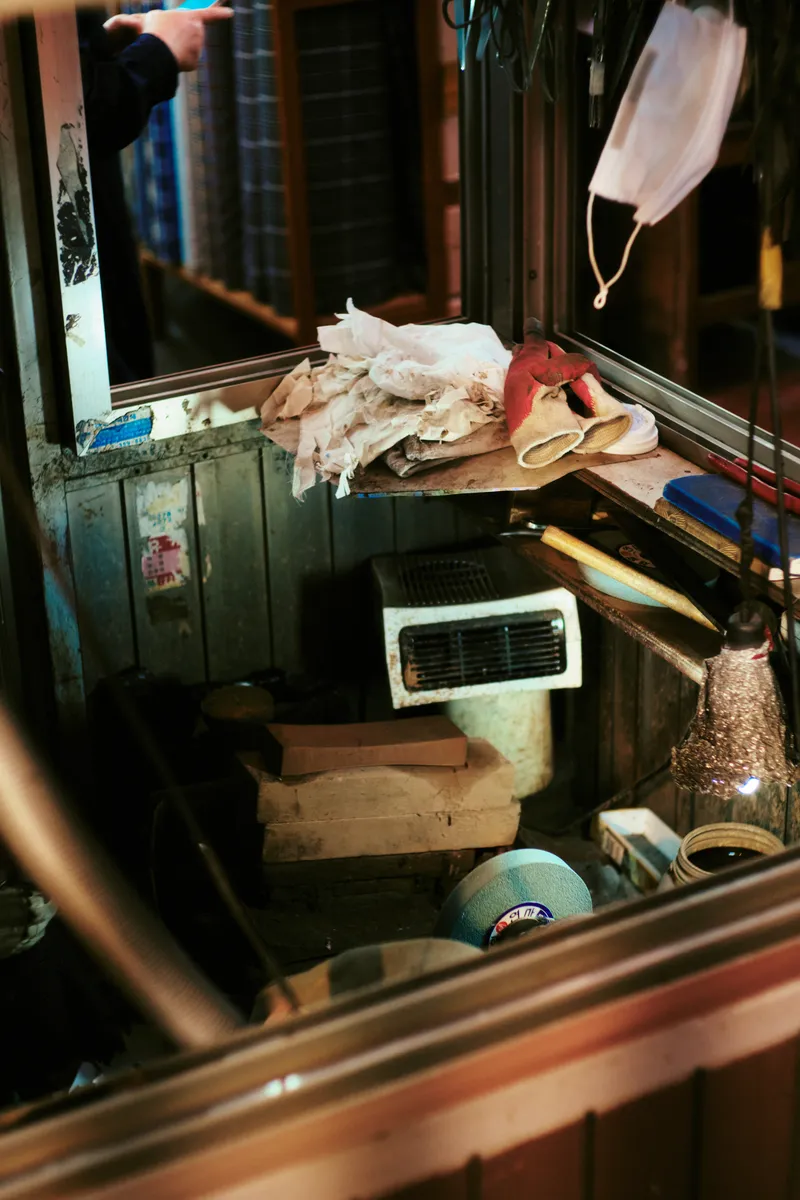 Cluttered shop corner with scattered fabric, tools and a face mask