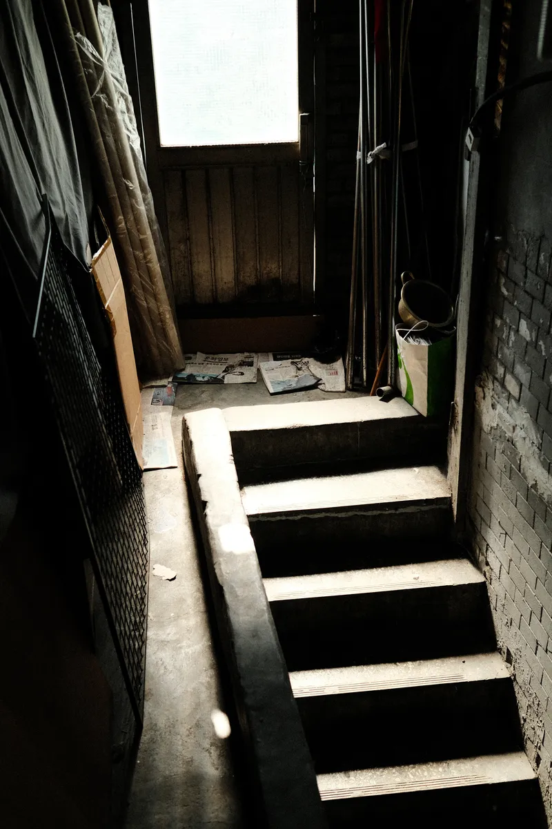 Narrow stairs lit from a skylight in a dark passage