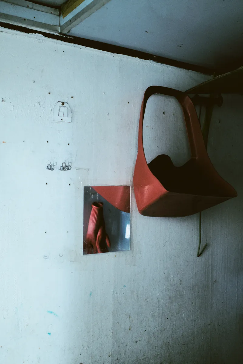 Orange wall-mounted chair and a small mirror on a white wall