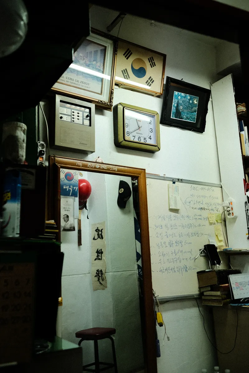 Small office wall with framed pictures, a clock and a stool