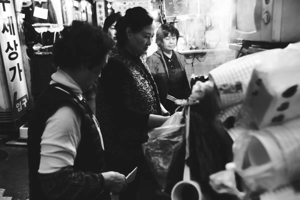 Women working together at a market stall, in black and white