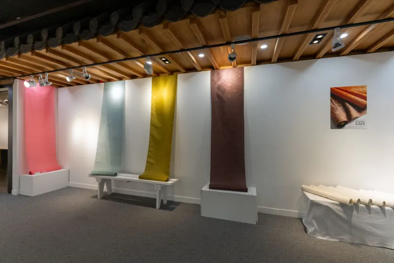 Lengths of naturally dyed silk hanging in a gallery