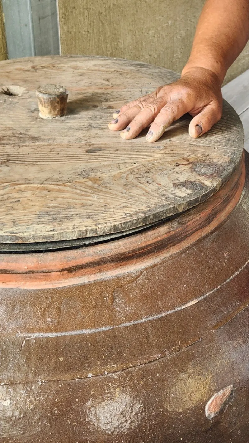 A hand on the wooden lid of an onggi jar