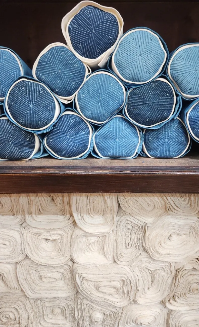 Quilted rolls of indigo cloth from pale sky to nearly black