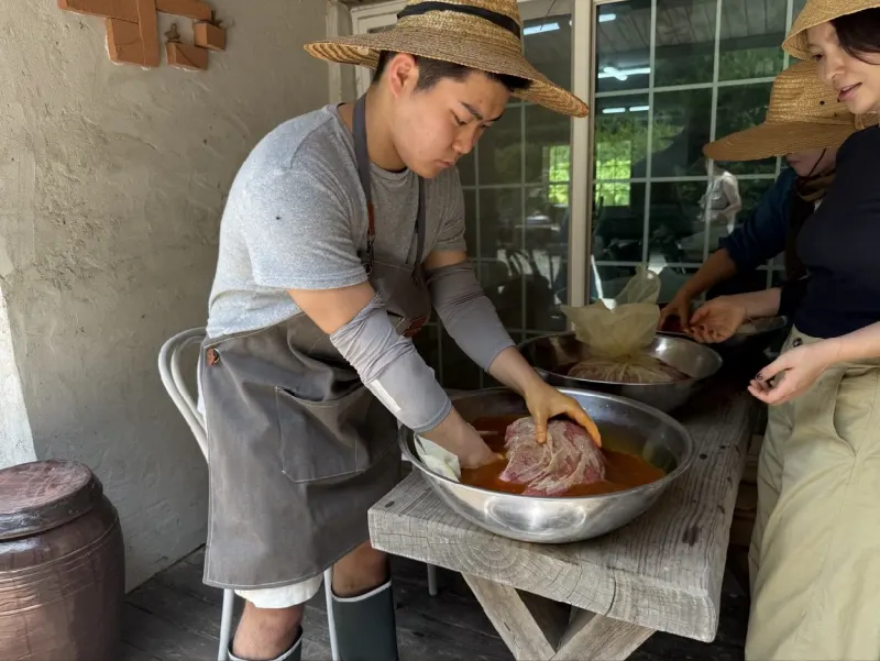 Kneading a cloth bag of safflower petals in a basin of water