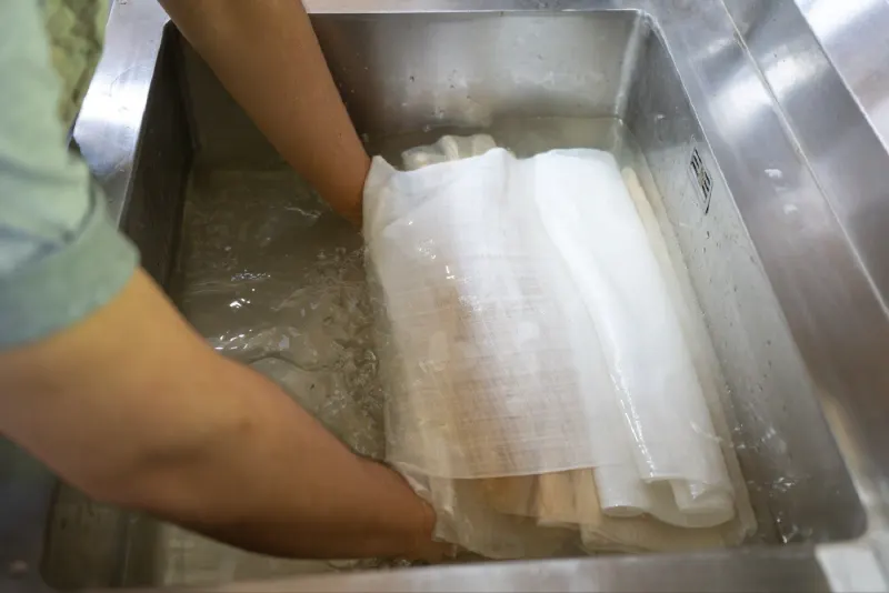 Wetting white cloth in a steel sink before dyeing