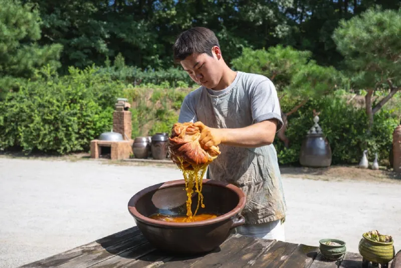 Squeezing yellow liquid from a bag of safflower petals into a bowl