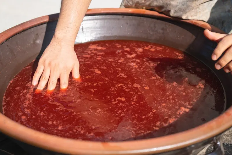 A hand resting in the red dye bath